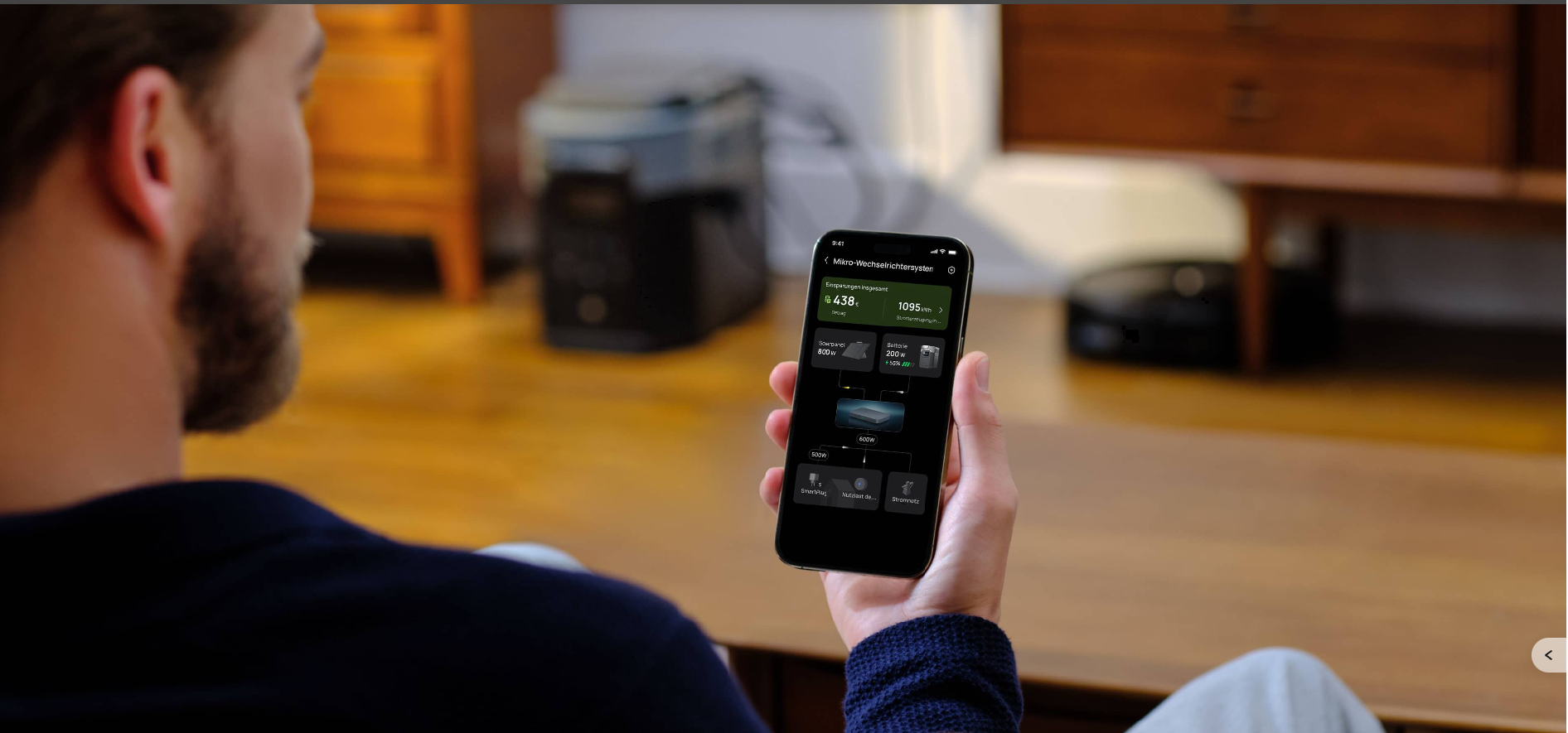 Person holding a phone with EcoFlow energy controls beside a power station at home