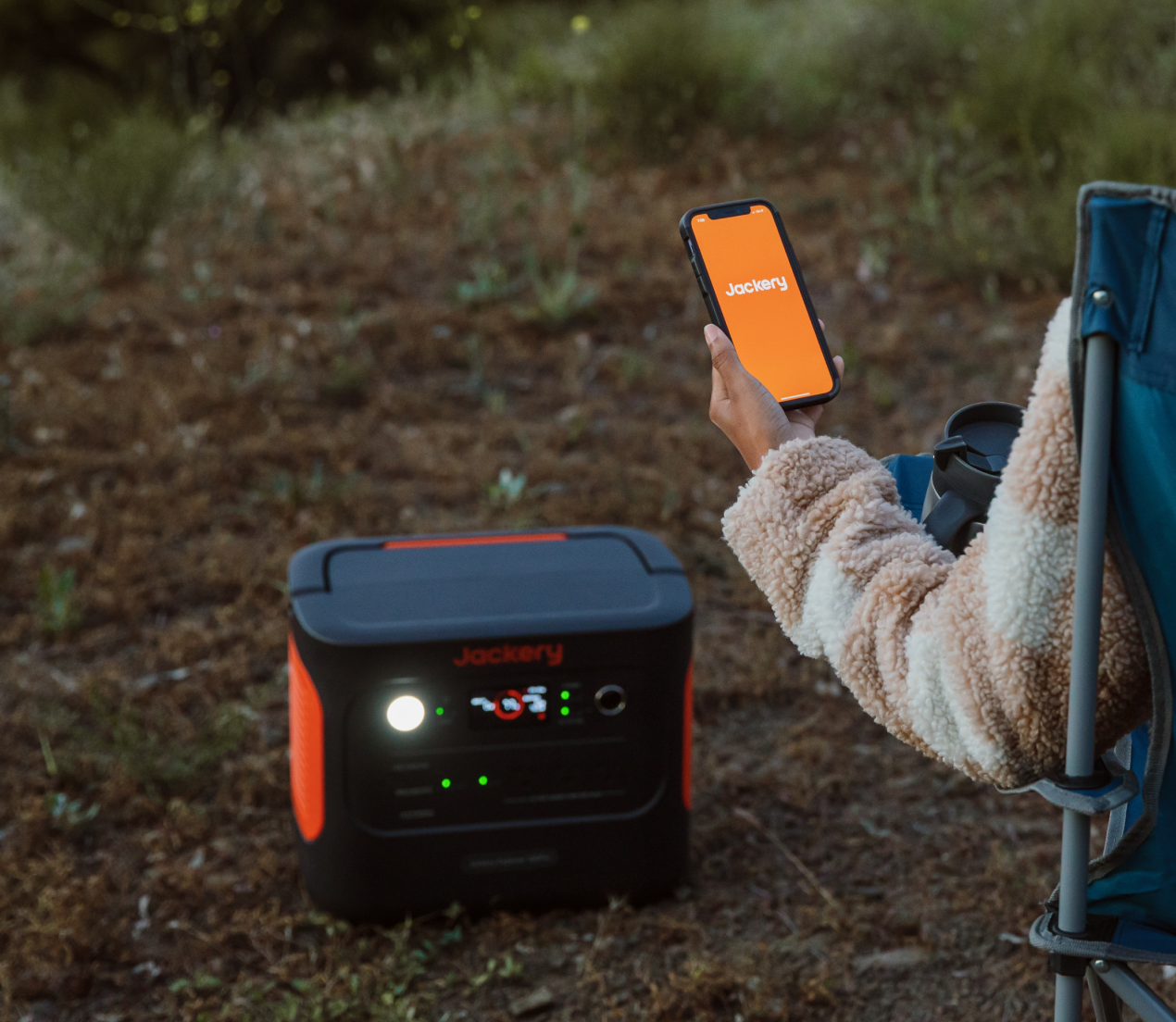 Camper holding a phone with the Jackery app beside an Explorer power station
